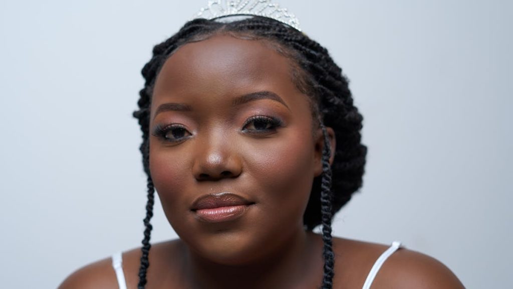 Elegant bride with braided hair and tiara, captured indoors in Lusaka, Zambia.